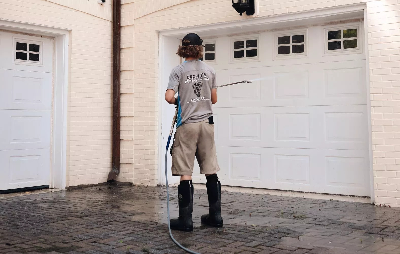 Brown's professional in black boots cleaning garage door
