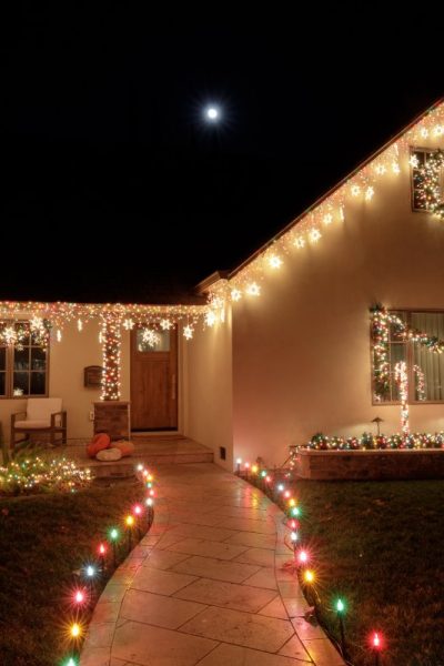 Christmas lights decorating house at night with full moon